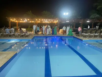a group of people standing around a swimming pool at night at Hacienda Villa Hermelina-Casa Campestre in Turbaco