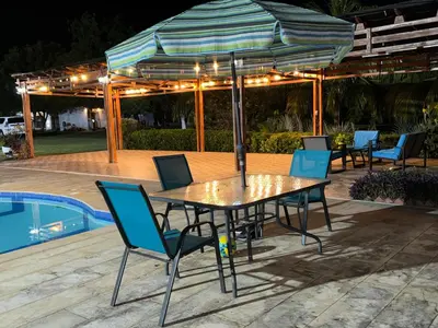 a table with chairs and an umbrella next to a pool at Hacienda Villa Hermelina-Casa Campestre in Turbaco