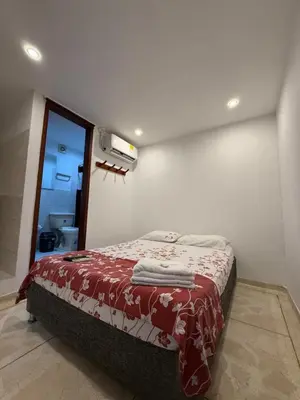 a bedroom with a bed with a red and white blanket at Hostal El Recreo in Barranquilla