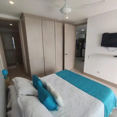 a bedroom with a bed with blue pillows on it at Palmetto Sunset in Cartagena de Indias