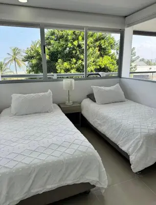 two beds in a bedroom with two windows at Hermoso apartamento moderno con vista al mar in Cartagena de Indias