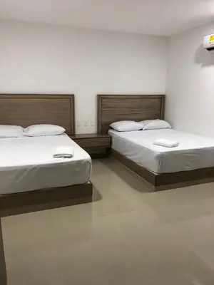 two beds in a hotel room with white sheets at Hotel Brisas in Tierra Bomba