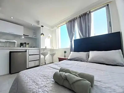 a bedroom with a large white bed with a large window at PISO 12 Cerca a la playa, Piscina, Wifi, AC in Cartagena de Indias