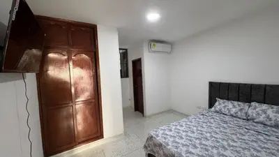 a bedroom with a bed and a wooden cabinet at Apartamento central en Barranquilla in Barranquilla