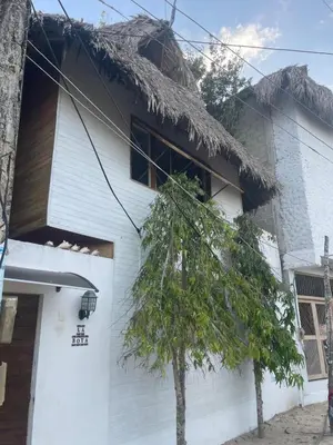 a white house with a thatch roof at Cabaña la bota in Rincón