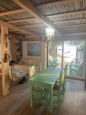 a dining room with a green table and chairs at Cabaña la bota in Rincón