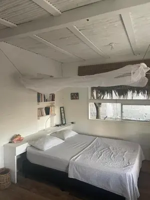 a bedroom with a white bed and a window at Cabaña la bota in Rincón