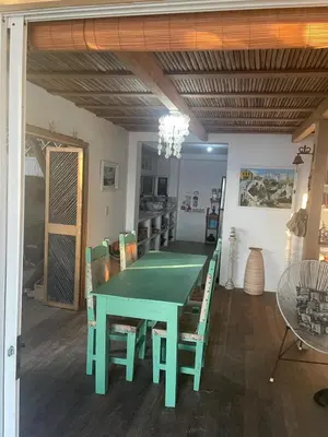 a dining room with a green table and chairs at Cabaña la bota in Rincón