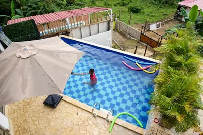 a child standing in a swimming pool with an umbrella at Arumake in Turbaco