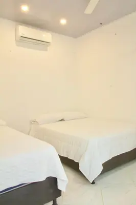 a white bedroom with two beds and a heater at Cabañas El Laguito Coveñas in Coveñas