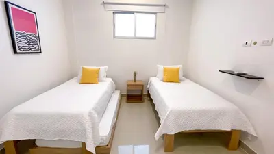 two beds in a room with white walls and yellow pillows at Magico Apartamento Frente al Mar 4 Habitaciones BM43 in Coveñitas
