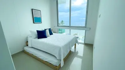 a bedroom with a bed with blue pillows and a window at Magico Apartamento Frente al Mar 4 Habitaciones BM43 in Coveñitas