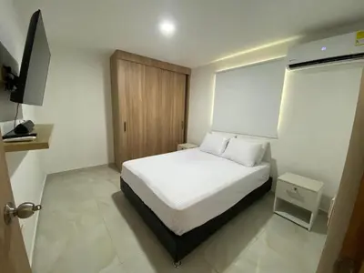 a bedroom with a white bed and a wooden door at Apartamento Sabaii 201 in Cartagena de Indias