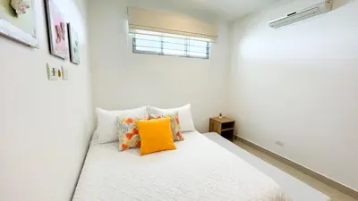 a bedroom with a white bed with an orange pillow at Magico Apartamento Frente al Mar 3 Habitaciones AR12 in Coveñas