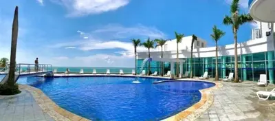 a large swimming pool with palm trees and the ocean at Inolvidables atardeceres en Cartagena in Cartagena de Indias