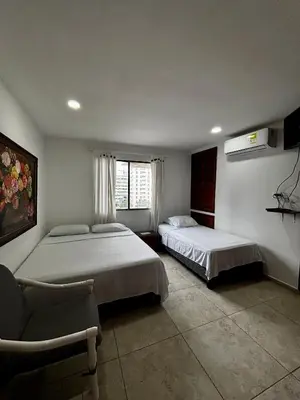 a bedroom with two beds and a chair and a window at Apartamentos en Bocagrande frente al mar in Cartagena de Indias