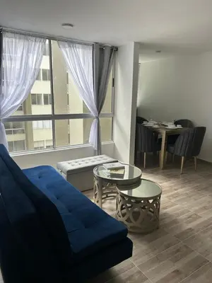 a living room with a blue couch and a table at Apartamento en Barranquilla in Puerto Colombia