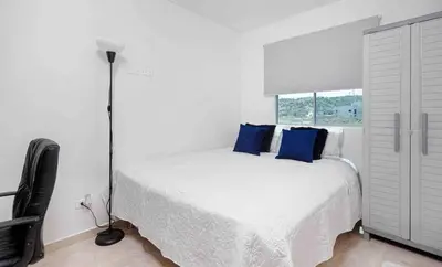 a white bedroom with a bed with blue pillows at Luxury CTG Condo Near Beach Cold AC & Hot Water in Cartagena de Indias