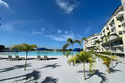 a beach with chairs and palm trees next to a building at 1ra Cristal Lagoons de Colombia in Cartagena de Indias
