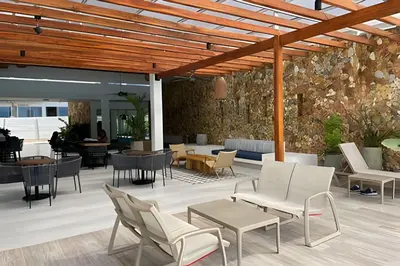a patio with chairs and tables and a stone wall at 1ra Cristal Lagoons de Colombia in Cartagena de Indias