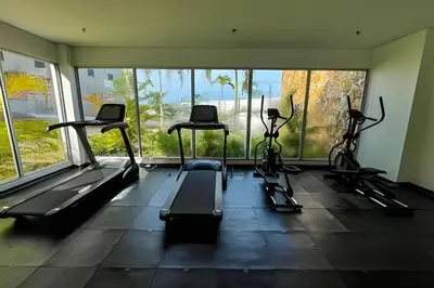 a gym with treadmills and ellipticals in a room with windows at 1ra Cristal Lagoons de Colombia in Cartagena de Indias