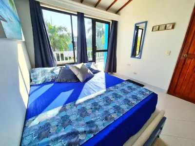 a bedroom with a blue bed and a window at Lujosa cabana con piscina playa y servicio in San Silvestre
