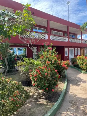 a red building with flowers in front of it at Las Margaritas Frente al Mar 2 in Coveñas