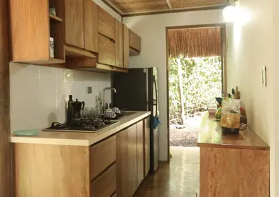 a kitchen with wooden cabinets and a black refrigerator at City Escape Casa Mariguana in Turbaco