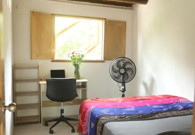 a room with a desk and a chair and a fan at City Escape Casa Mariguana in Turbaco