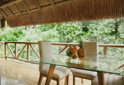a glass table with a pineapple and chairs on a balcony at City Escape Casa Mariguana in Turbaco