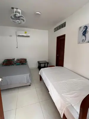 two beds in a room with white walls at Asís apartamentos in Tolú