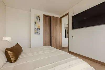 a white bedroom with a large bed and a flat screen tv at Vista al Mar/ Centro Histórico/ Nuevo Piso 26 1BR in Cartagena de Indias