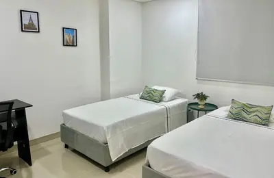 two beds in a room with a desk and a window at Escapada 2BR en Ocean Drive in Cartagena de Indias