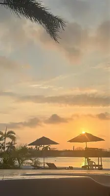 two umbrellas sitting on a beach with the sunset at baia kristal paraiso aguas cristalinas in Cartagena de Indias