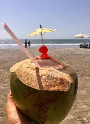 a person holding a coconut with an umbrella on the beach at Morros Vitri Disfruta de acceso directo a la playa in Cartagena de Indias