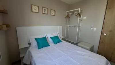 a bedroom with a white bed with two blue pillows at Apto bien ubicado cerca al mar, cerca al centro y al aereopuerto in Cartagena de Indias