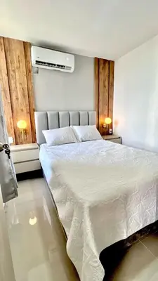 a bedroom with a large white bed with two lamps at Encanto cerca al mar in Cartagena de Indias