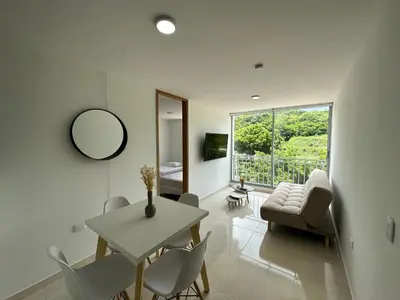 a white living room with a table and chairs at Apto con vista verde y aire acondicionado in Barranquilla