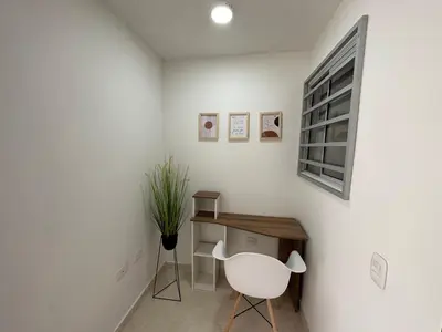 a white room with a desk and a white chair at Apto con vista verde y aire acondicionado in Barranquilla