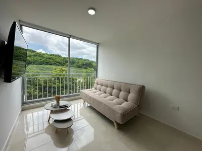 a living room with a couch and a large window at Apto con vista verde y aire acondicionado in Barranquilla