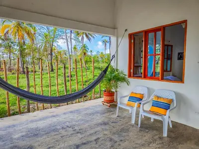 a room with two chairs and a hammock on a porch at Casa Blanca Broqueles Hotel in Moñitos