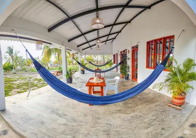 a hammock in a porch with a table and chairs at Casa Blanca Broqueles Hotel in Moñitos