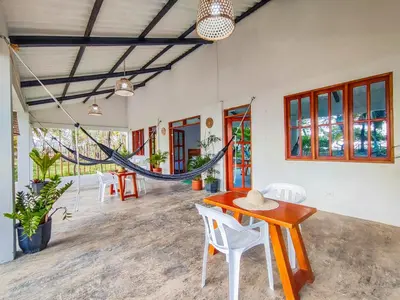 a room with tables and chairs and a hammock at Casa Blanca Broqueles Hotel in Moñitos
