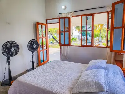 a bedroom with a bed with a fan and windows at Casa Blanca Broqueles Hotel in Moñitos