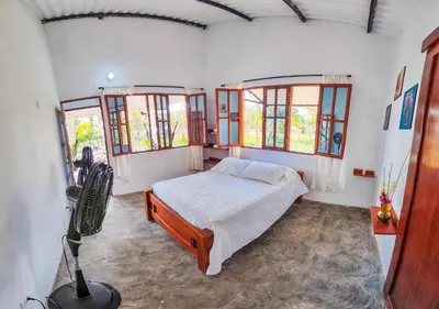 a bedroom with a bed in a room with windows at Casa Blanca Broqueles Hotel in Moñitos