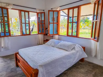 a bedroom with a bed in a room with windows at Casa Blanca Broqueles Hotel in Moñitos