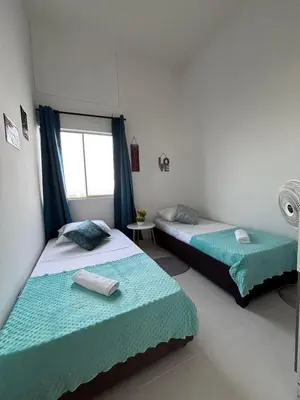 two beds in a room with blue curtains and a window at B lounge experience ctg bolívar in Cartagena de Indias