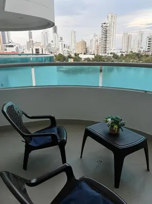 a chair and a table on a balcony with a view of a city at Ocean and Lagoon View Apartment in Cartagena El Laguito 804A in Cartagena de Indias