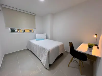 a bedroom with a bed and a desk and a chair at Cozy and close to the airport in Cartagena de Indias