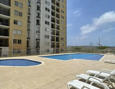 a swimming pool with white chairs next to a building at Apartment in Alameda del Río in Barranquilla